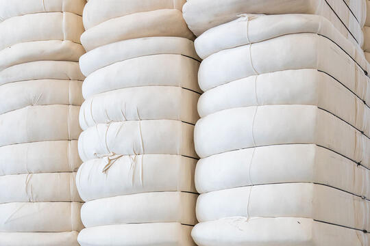 Cotton bales placed on each other in a mill storage - click on the link to see the webinar recording about raw material management